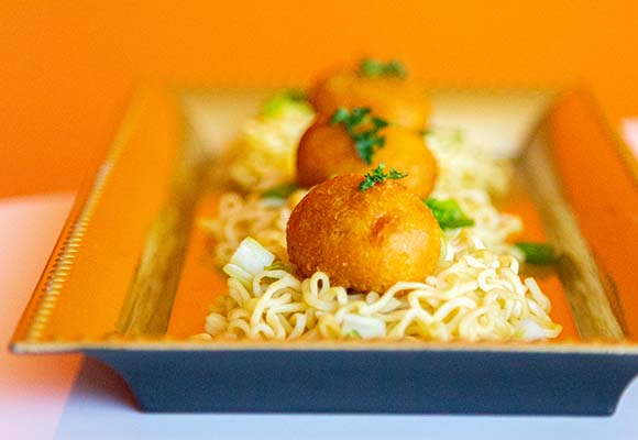 Three mini corn dogs on top of small beds ramen noodles