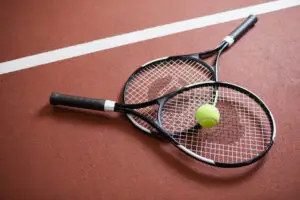 two tennis rackets and a tennis ball stacked on a tennis court